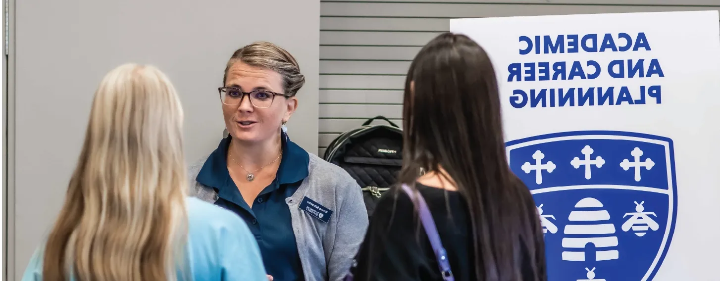 Career center staff talking to students at information fair.