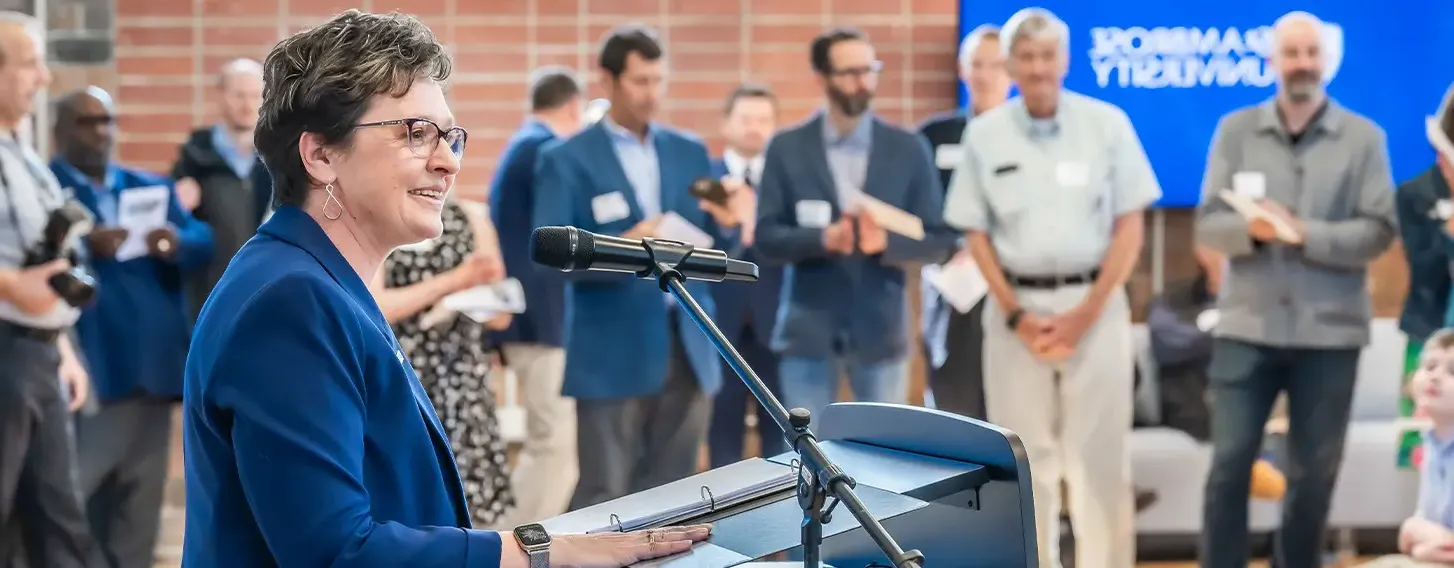 Dr. Amy Novak speaking in front of a crowd in the new Higgins Hall